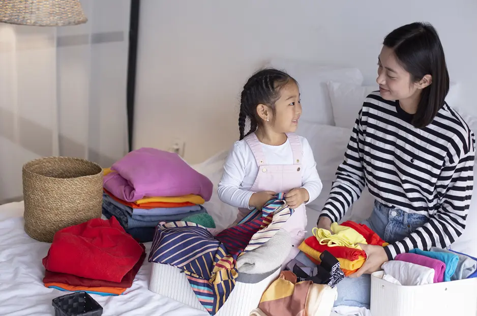 親子で洋服を畳み箱に収めている様子